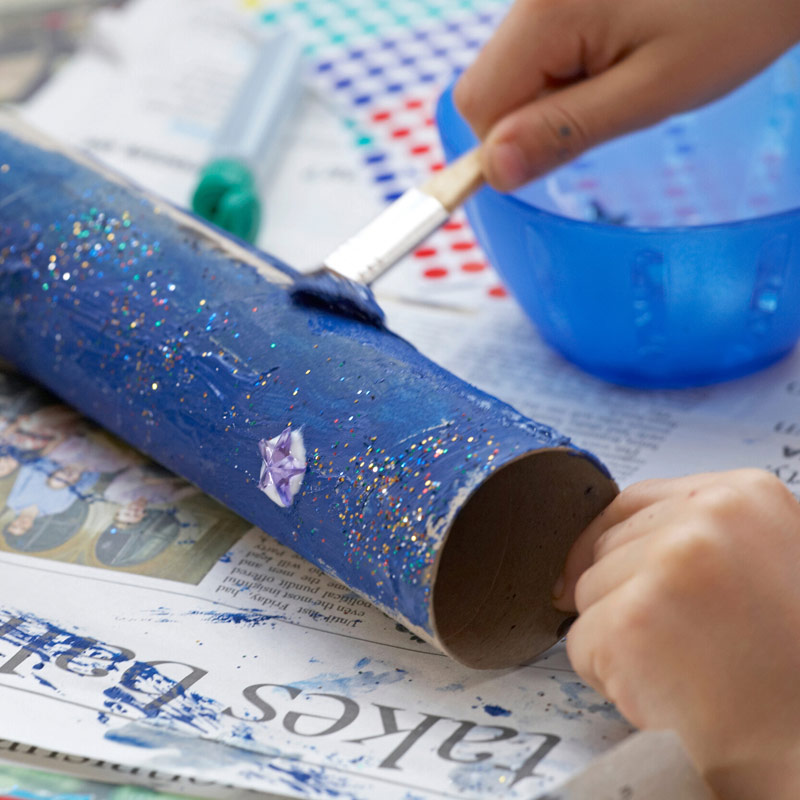 Child painting a cardboard tube