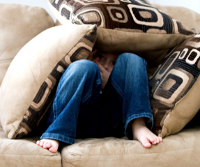 Boy hiding under cushions