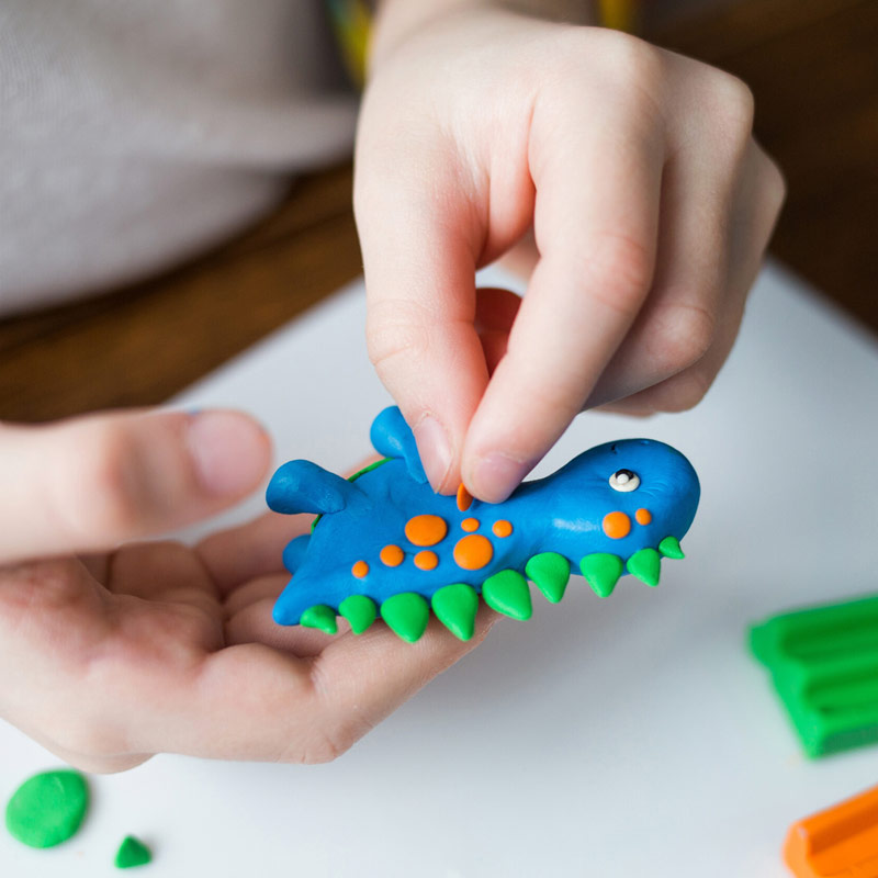 Hands creating a modellingn clay dinosaur