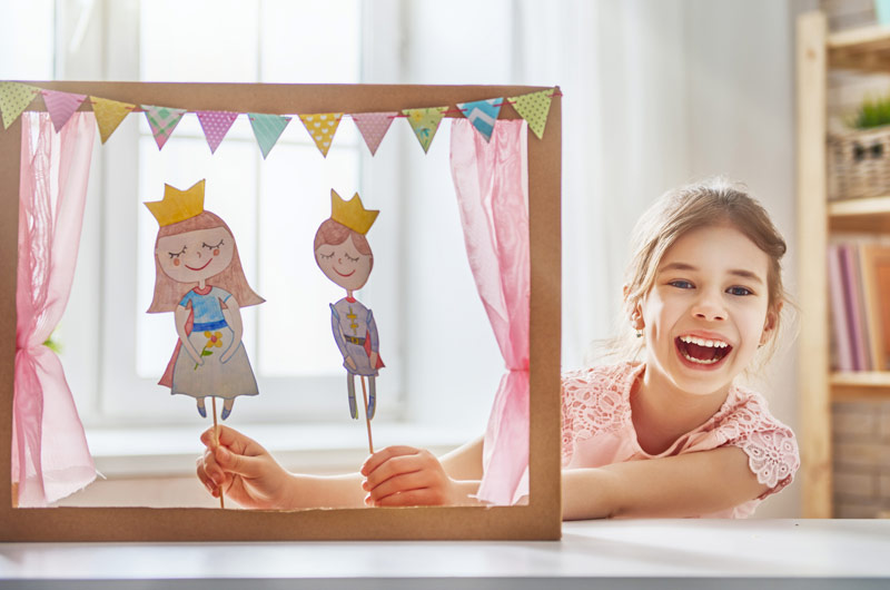 Girl playing with a puppet theatre